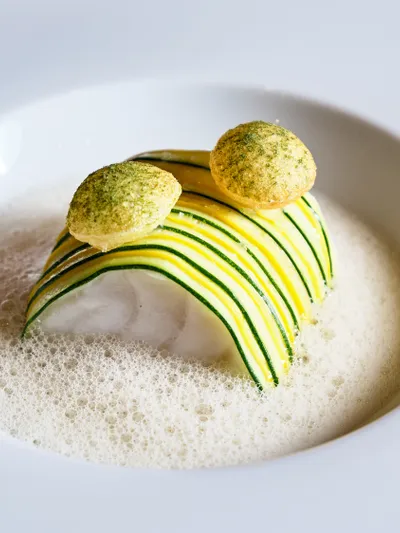 Gourmetgericht mit gestreiften Zucchini, Schaumsauce und zwei Kräuterchips